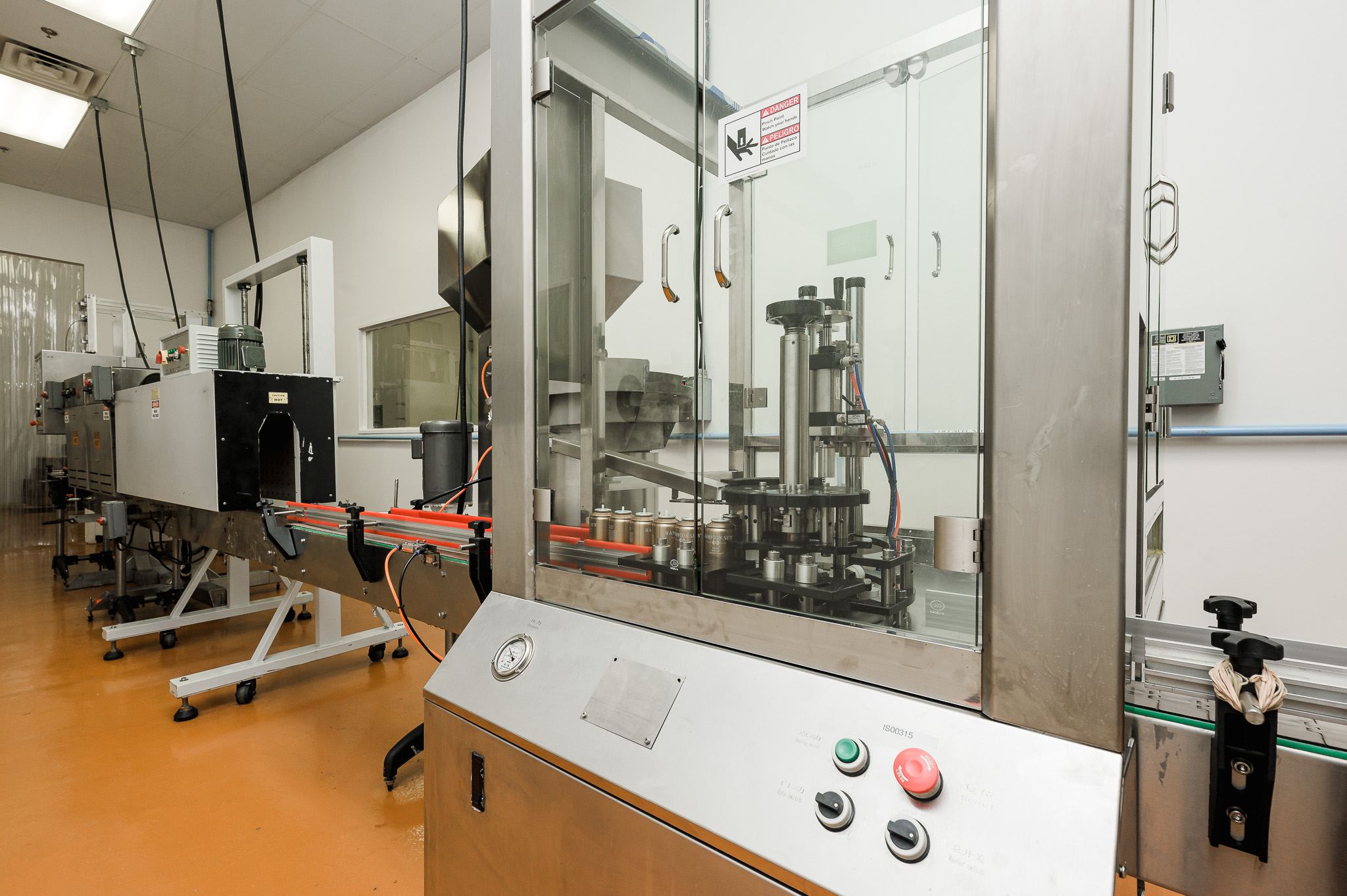 Aerosol cans moving through capping and finishing equipment