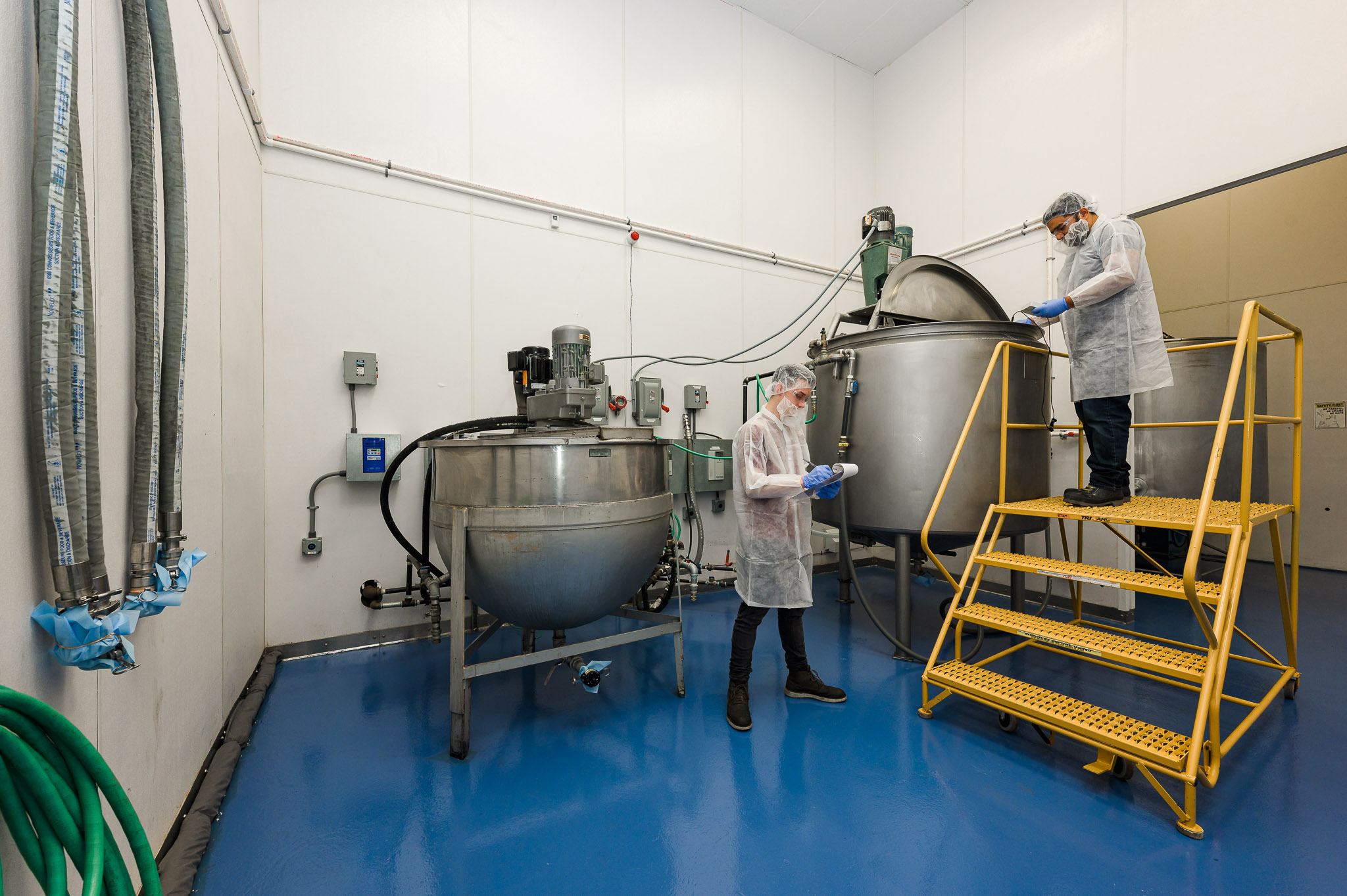 Technicians compounding a batch at stainless steel kettles