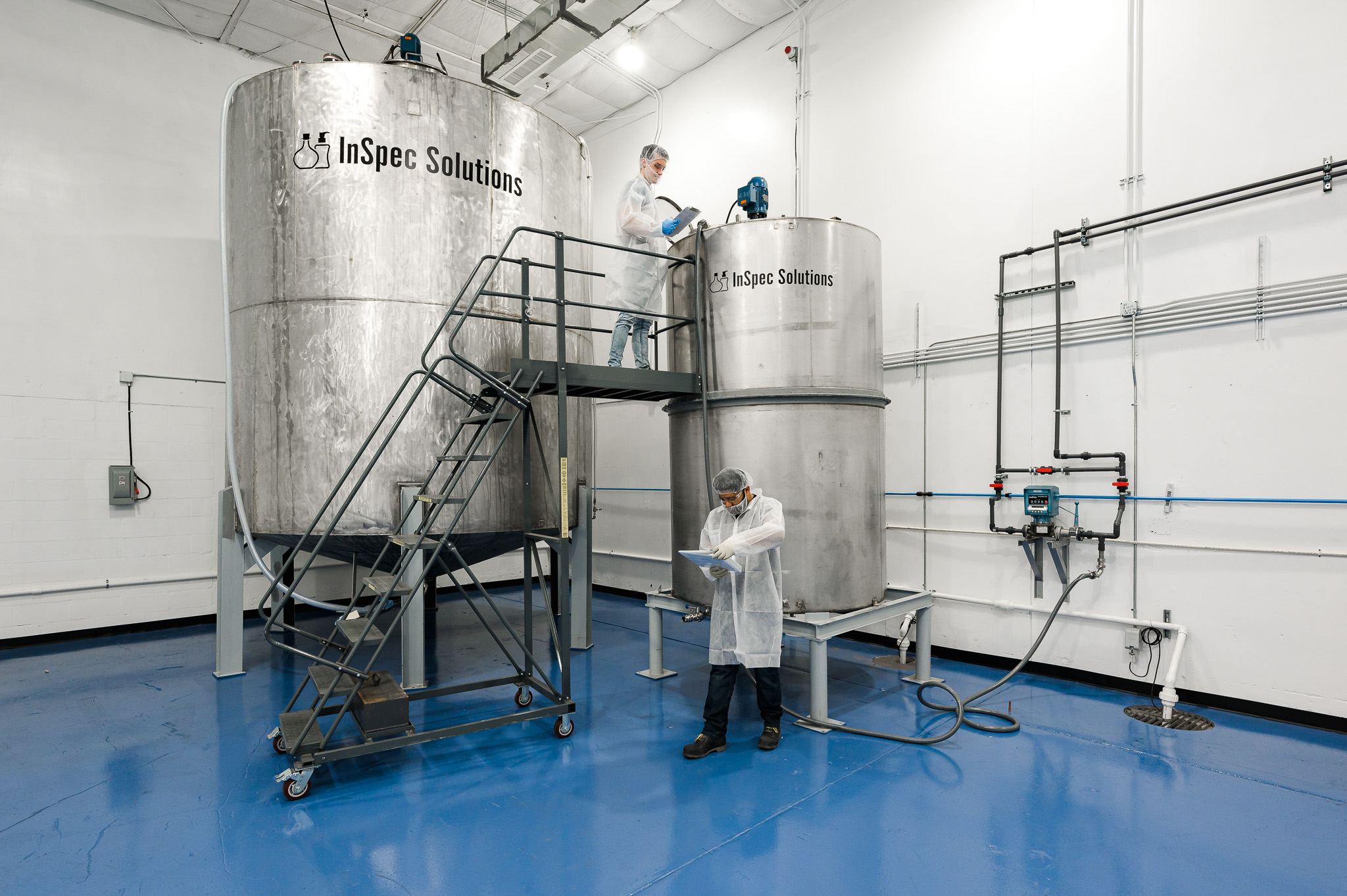 Technicians working at InSpec stainless steel mixing tanks