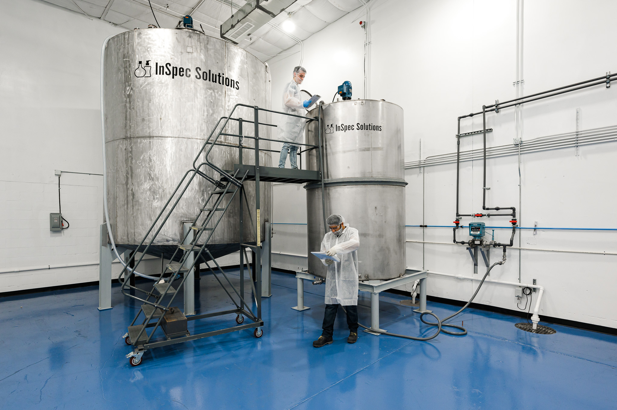 Technicians working at InSpec stainless steel mixing tanks